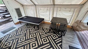 Ein Zeltraum mit einem Bett, einem kleinen Tisch und einer Bank.