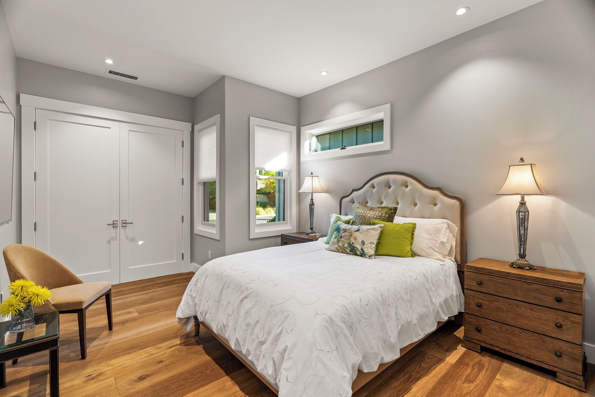 A bedroom with a large bed, a nightstand, a chair, and a wardrobe.