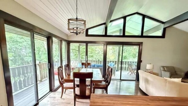 Una habitación amplia con una mesa de comedor de madera, un sofá y puertas correderas de vidrio que dan a una terraza al aire libre.