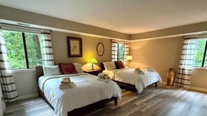 Habitación de hotel con dos camas, un ventanal grande y suelo de madera.