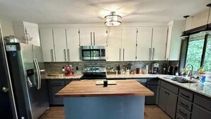 Una cocina moderna con una isla central, electrodomésticos de acero inoxidable y vistas al exterior.
