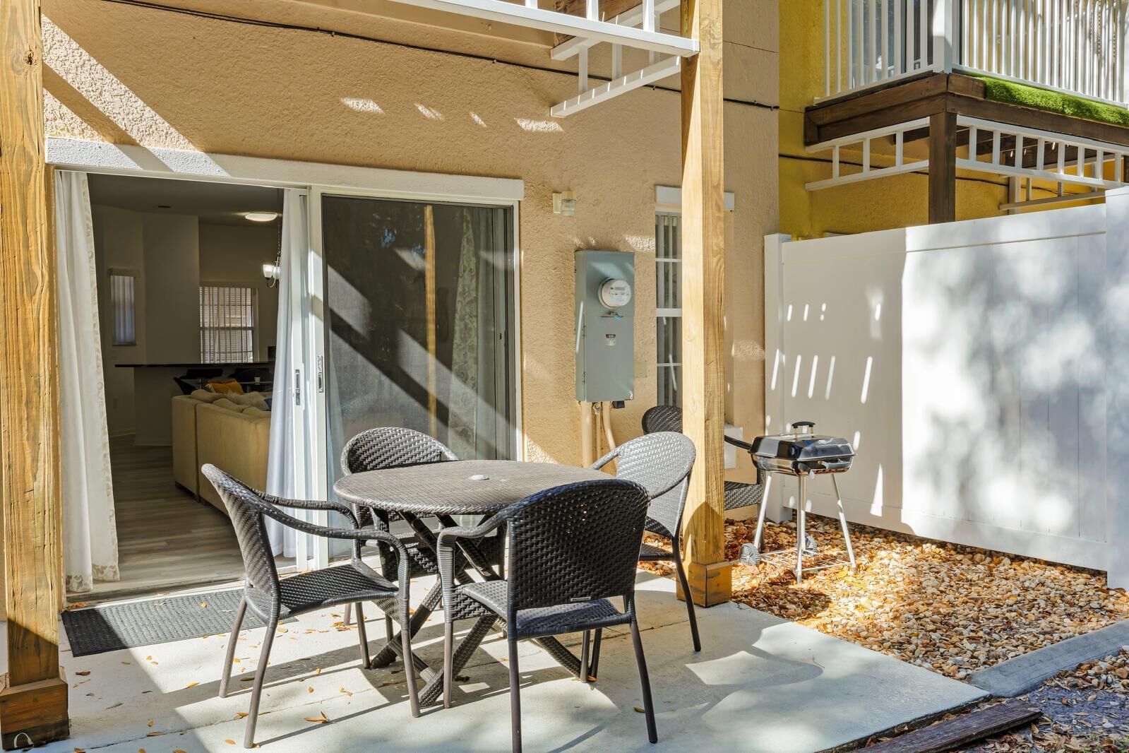 An outdoor patio with a table and chairs, a barbecue grill, and a sliding glass door leading to an interior space.