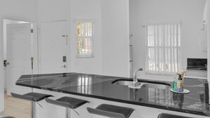 A modern kitchen with a black marble countertop, stainless steel sink, and bar stools.