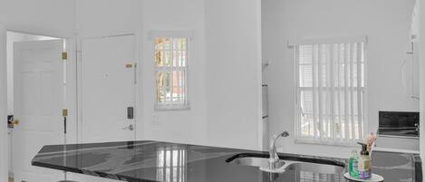 Una cocina moderna con encimera de mármol negro, pileta de acero inoxidable y taburetes de bar.