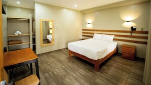 A hotel room with a wooden bed, a desk, a chair, a wardrobe, a mirror, and a nightstand. - Fundo San Rafael (Nazca)
