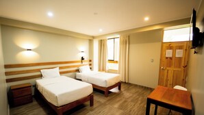 A hotel room with two single beds, a wooden desk, a chair, a nightstand, and a wooden wardrobe. - Fundo San Rafael (Nazca)