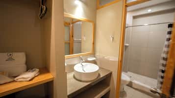 Un baño de hotel con lavamanos, espejo y ducha.