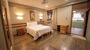 A hotel room with a bed, bedside table, and a view of the outdoors. - Fundo San Rafael (Nazca)