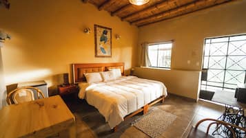 Un dormitorio con cama de madera, una mesa de comedor y sillas. Se ve una ventana con vistas al exterior.