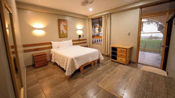 A hotel room with a bed, bedside table, and a view of the outdoors. - Fundo San Rafael (Nazca)