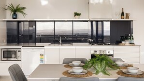 A modern kitchen with a central island, built-in appliances, and a dining area with a view. - Circle on Cavill Level 23 River View (Surfers Paradise)