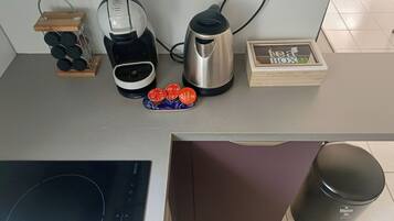Een keuken met een koffiezetapparaat, waterkoker en een doosje met thee.