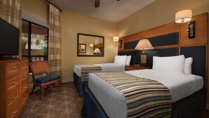 Une chambre d’hôtel avec deux lits, une télévision, un bureau et une chaise.