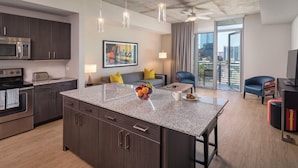 A modern kitchen with a granite countertop, stainless steel appliances, and a central island with fruit.