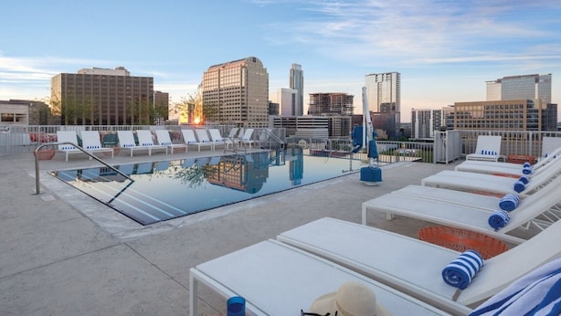 A rooftop pool with lounge chairs and a cityscape view.