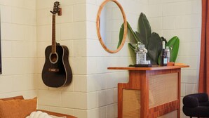 A room with a guitar, a round mirror, a wooden console table with a plant, and a woven basket. - 4 Min Walk to Beach & Restaurants (Manhattan Beach)