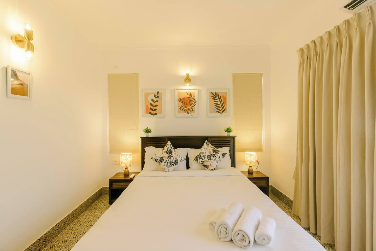 A hotel room with a large bed, two bedside tables with lamps, and decorative wall art.