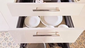 Un tiroir de cuisine contenant des assiettes, des bols et des ustensiles de cuisine, le tout de couleur blanche.