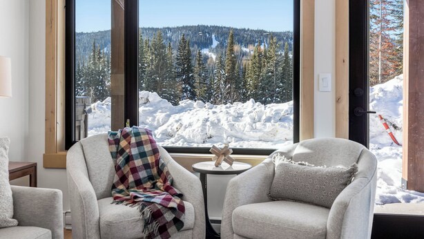 A cozy room with two armchairs facing a large window overlooking a snowy mountain landscape. - Switchback Creek Condo 4 (Sun Peaks)