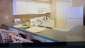 Una cocina compacta con armarios blancos, un microondas y un refrigerador.