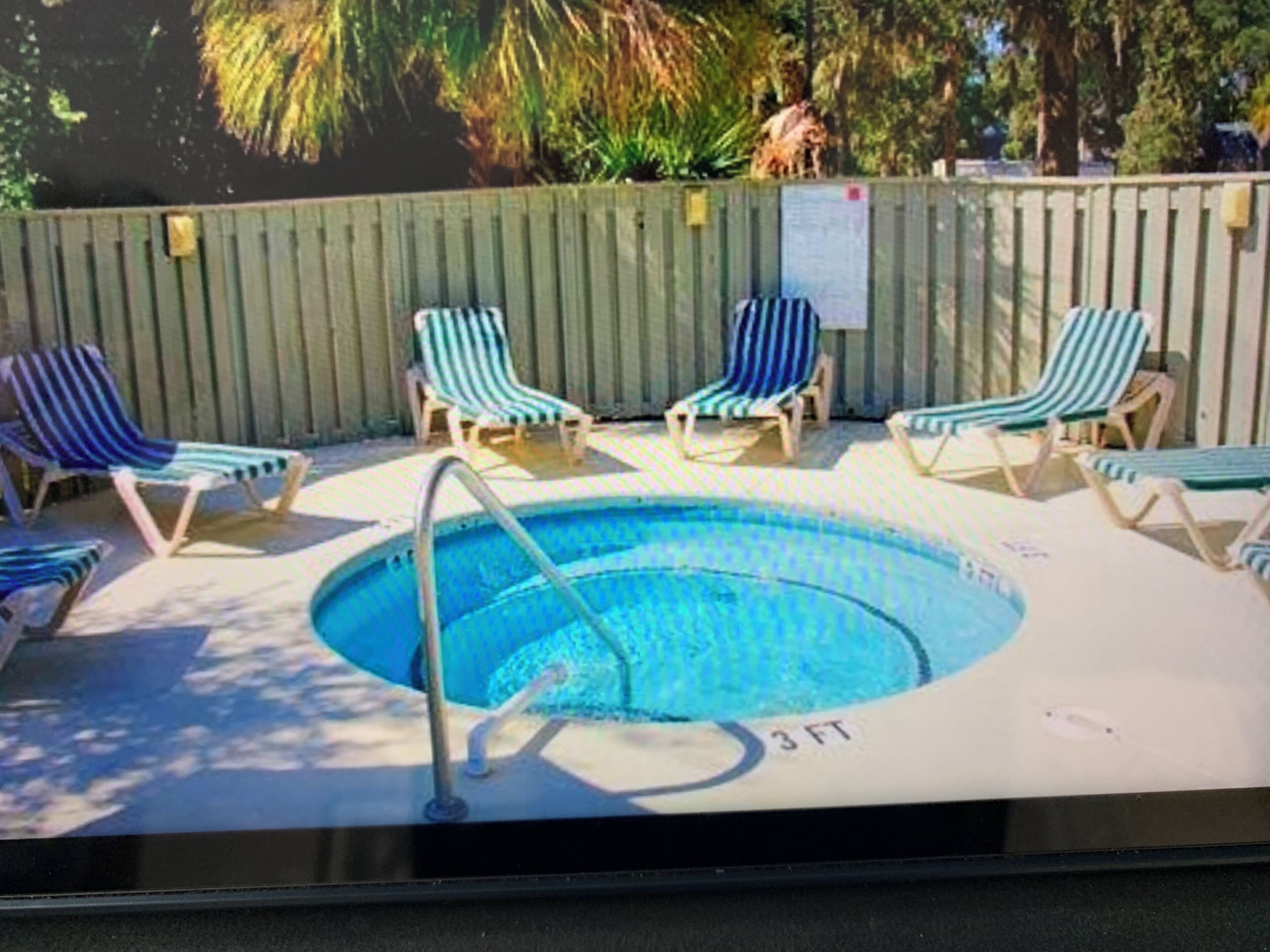 Una piscina con sillones de descanso y una valla de madera.