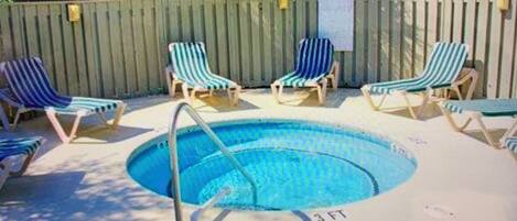 Una piscina con sillones de descanso y una valla de madera.