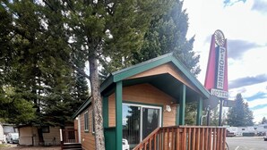 A small motel with a wooden exterior, a porch, and a staircase leading to the entrance. - Pioneer Motel  (West Yellowstone)