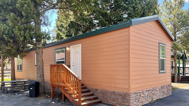 A small, single-story cabin with a wooden staircase leading to a door marked "21". - Pioneer Motel  (West Yellowstone)