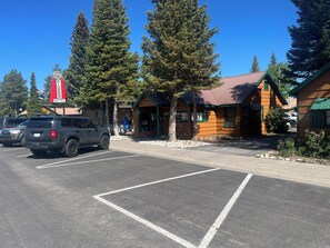 Un motel avec une enseigne rouge, des cabanes en bois et un parking.