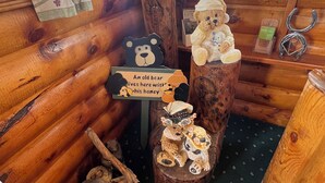 A rustic cabin interior with wooden walls, a bear-themed decoration, and a sign reading 'An old bear lives here with his honey.' - Pioneer Motel  (West Yellowstone)