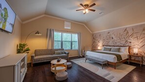 Ein Schlafzimmer mit einem Bett, einer Couch, einem Couchtisch und einem Deckenventilator.