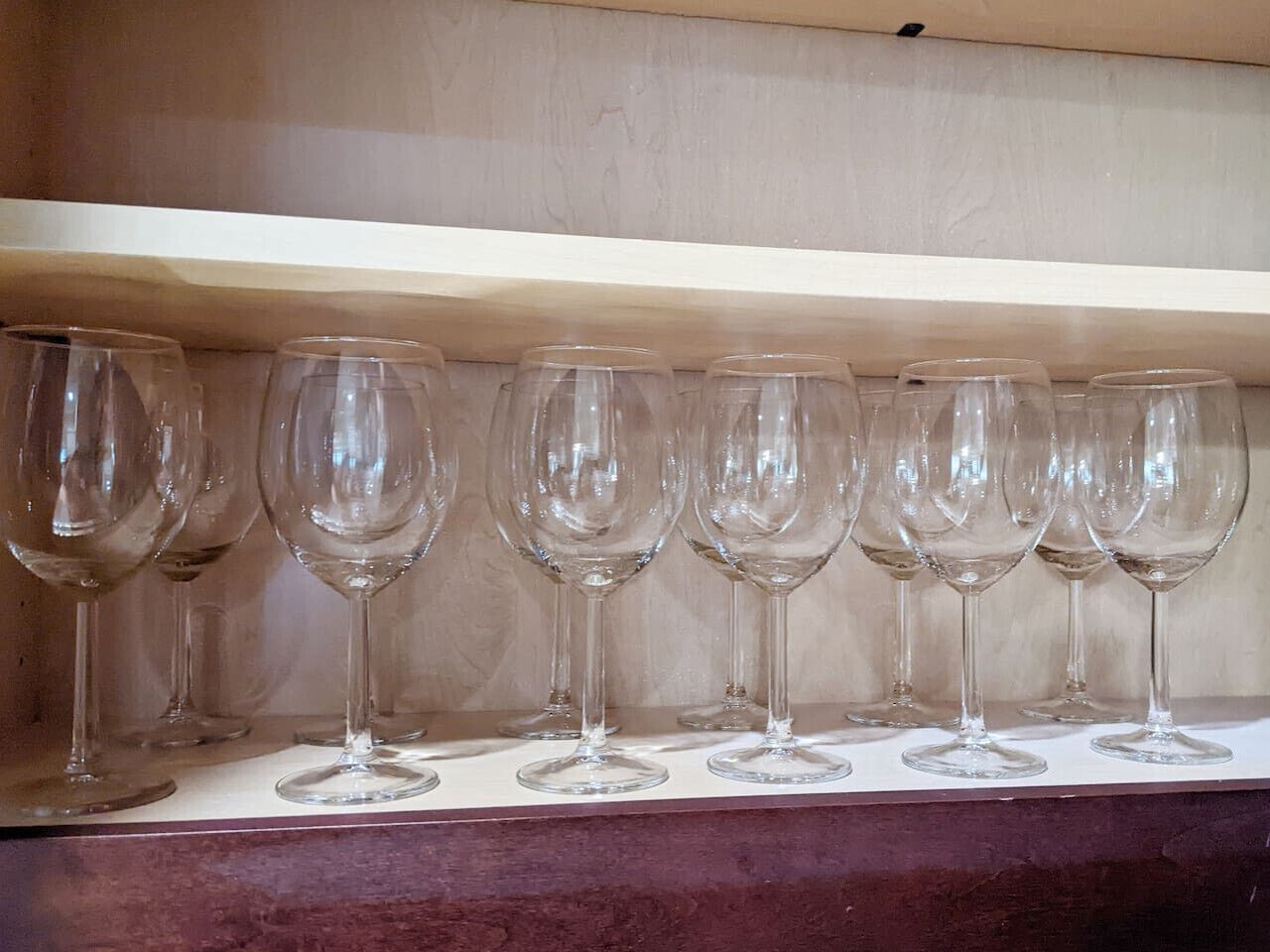 A shelf with multiple empty wine glasses.
