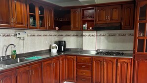 Una cocina con armarios de madera, estufa a gas, cafetera y lavaplatos.
