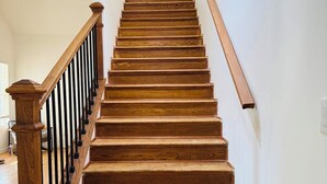 Una escalera de madera con barandilla y una ventana en la parte superior.