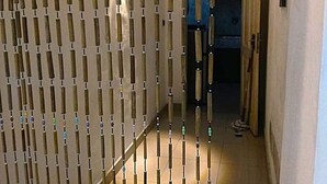Ein Flur mit einer Holzwand mit vertikalen Lamellen und bunten Perlen.