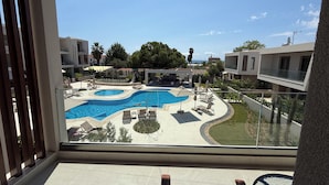 A view of a swimming pool area with lounge chairs and a slide, surrounded by buildings and trees. - Darion Townhouse (Nikiti)