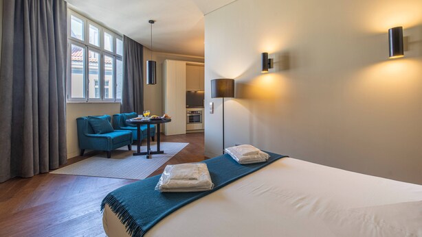 Et hotelværelse med en stor seng, en sofa, et lille bord og udsigt ud af vinduet.