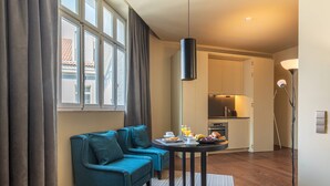 Et moderne hotelværelse med sofa, morgenmadsbord og udsigt udad.