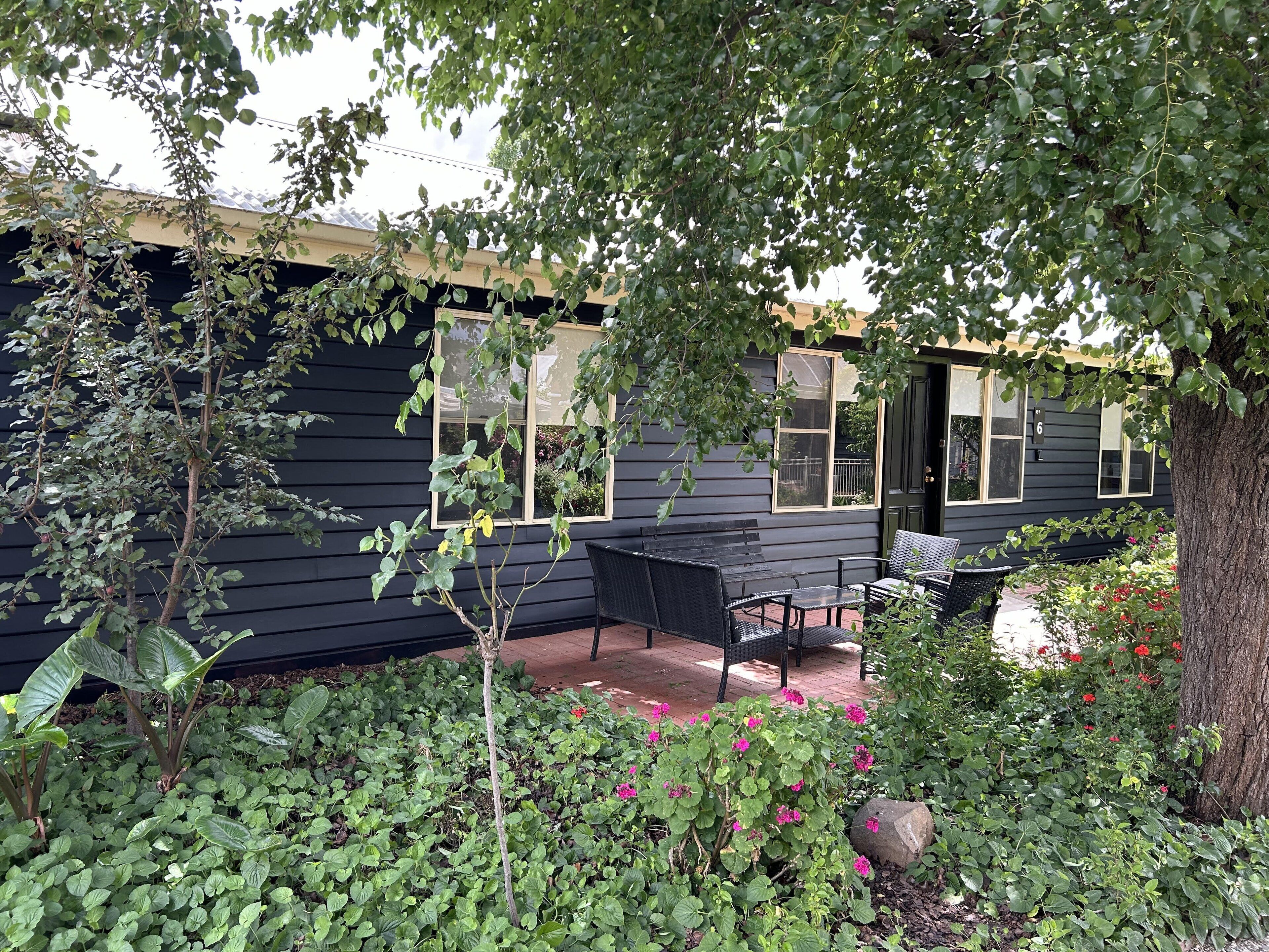 A black house with a porch, a bench, and a small table.