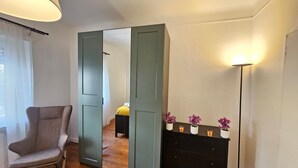A room with a large mirror, a chair, a dresser, and a floor lamp. - Ideal city stay 1BR near train station (Luxembourg City)
