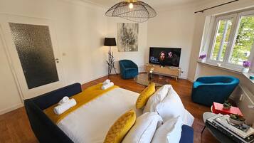 Una habitación de hotel moderna con una cama grande, dos sillones, un televisor y una ventana con vistas.
