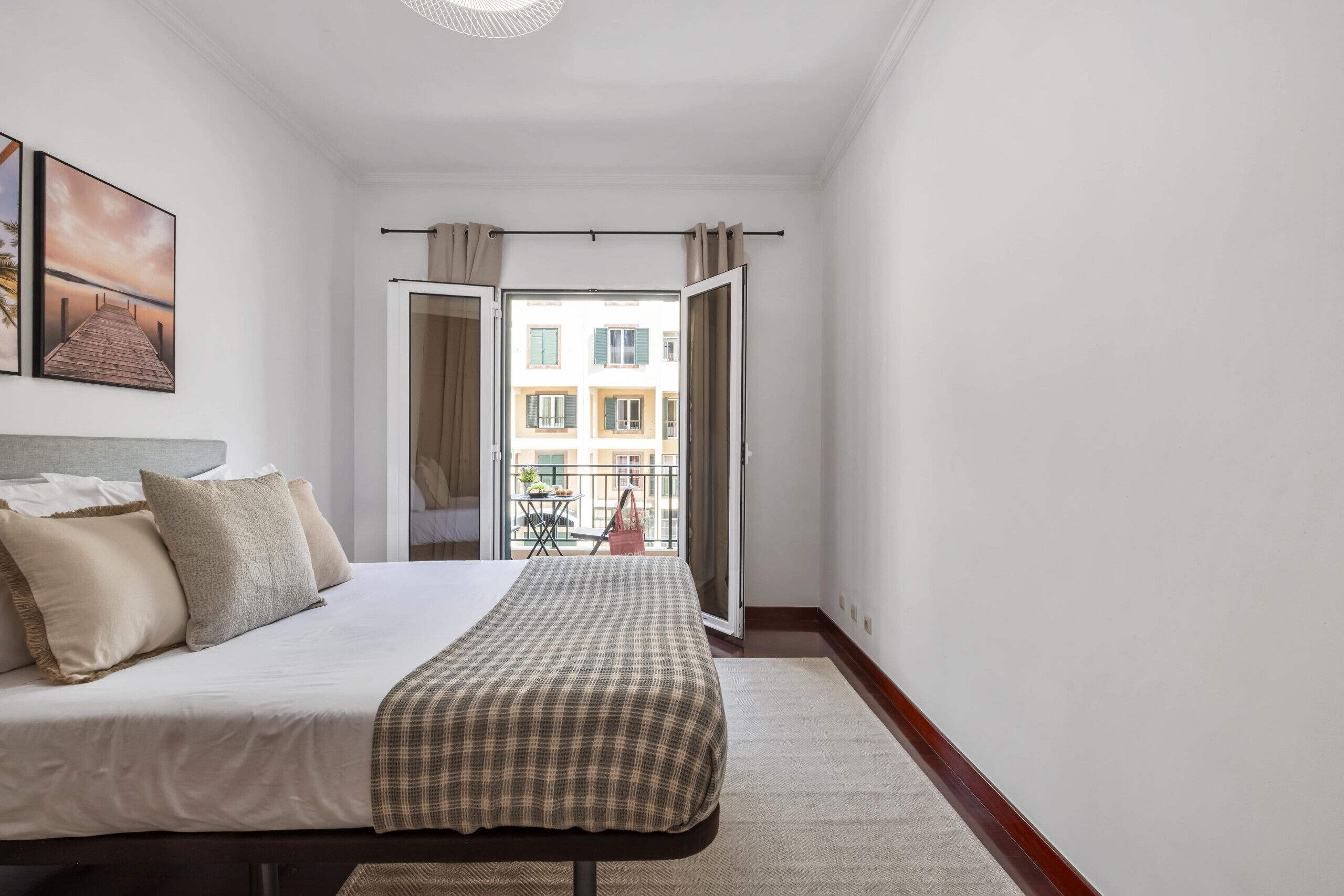 Ein Schlafzimmer mit Bett, Blick auf den Balkon und einem Fenster mit Vorhängen.