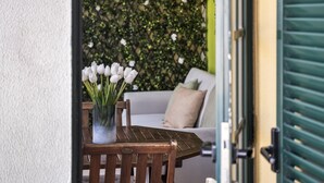 Ett träbord med en vas med vita blommor, en trästol och en grön dörr.
