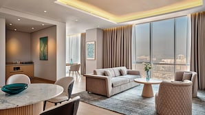 A modern living room with a sofa, armchairs, a coffee table, and a dining area with a table and chairs.