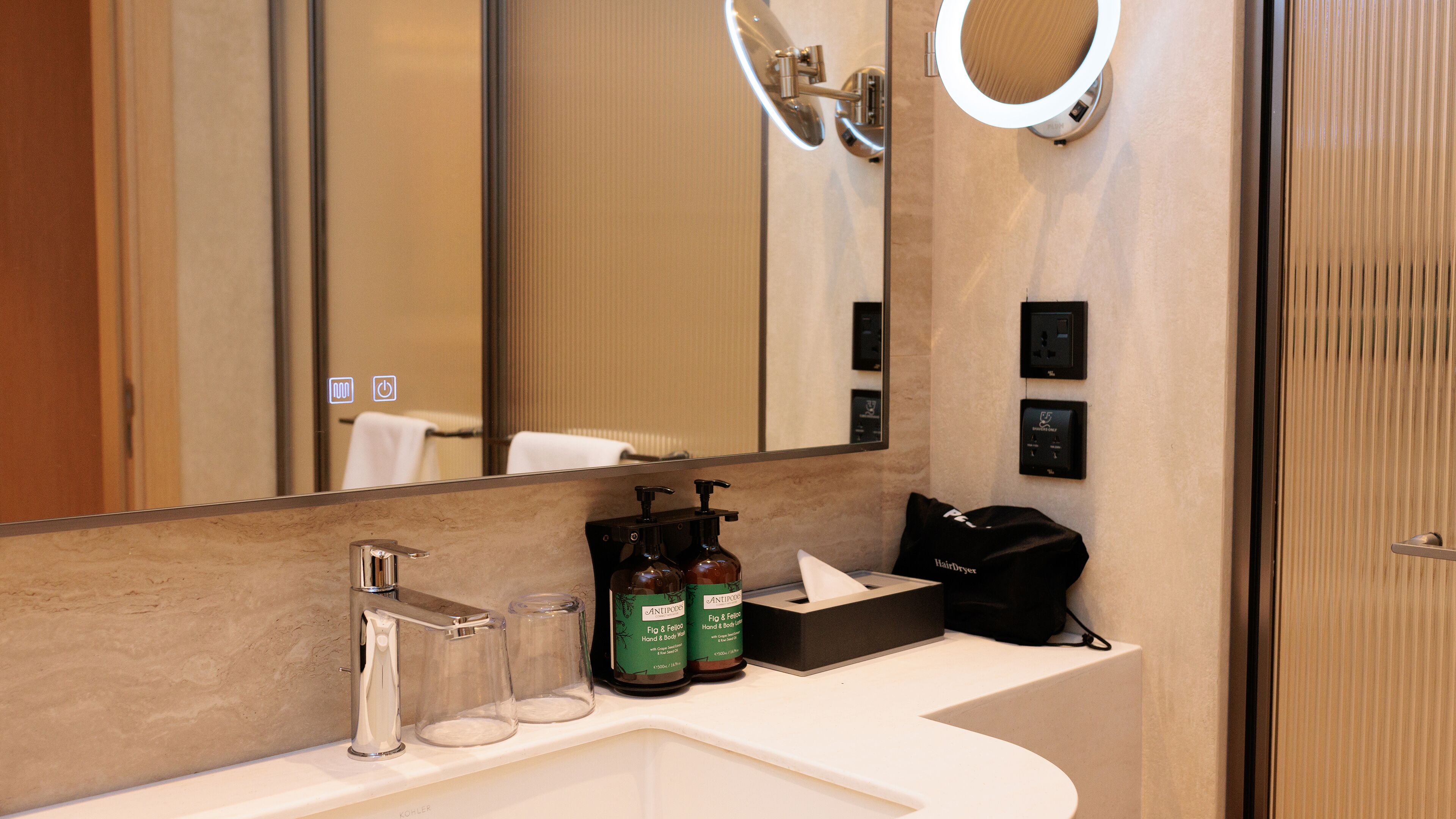 A modern bathroom with a large mirror, a sink, and toiletries.