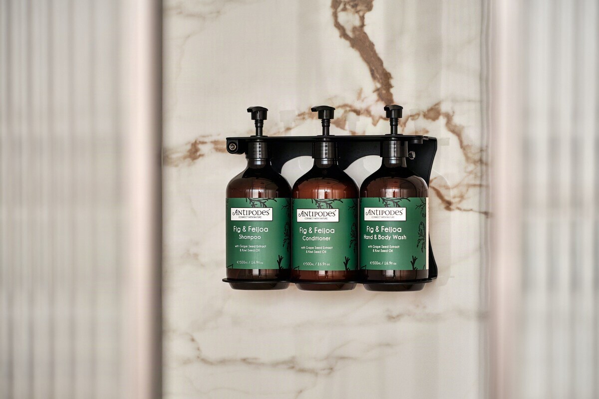 Three bottles of Antipodes products on a marble wall.
