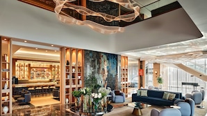A modern lobby with a bar area, seating, and a decorative light fixture. - Crowne Plaza Dushanbe by IHG (Dushanbe)