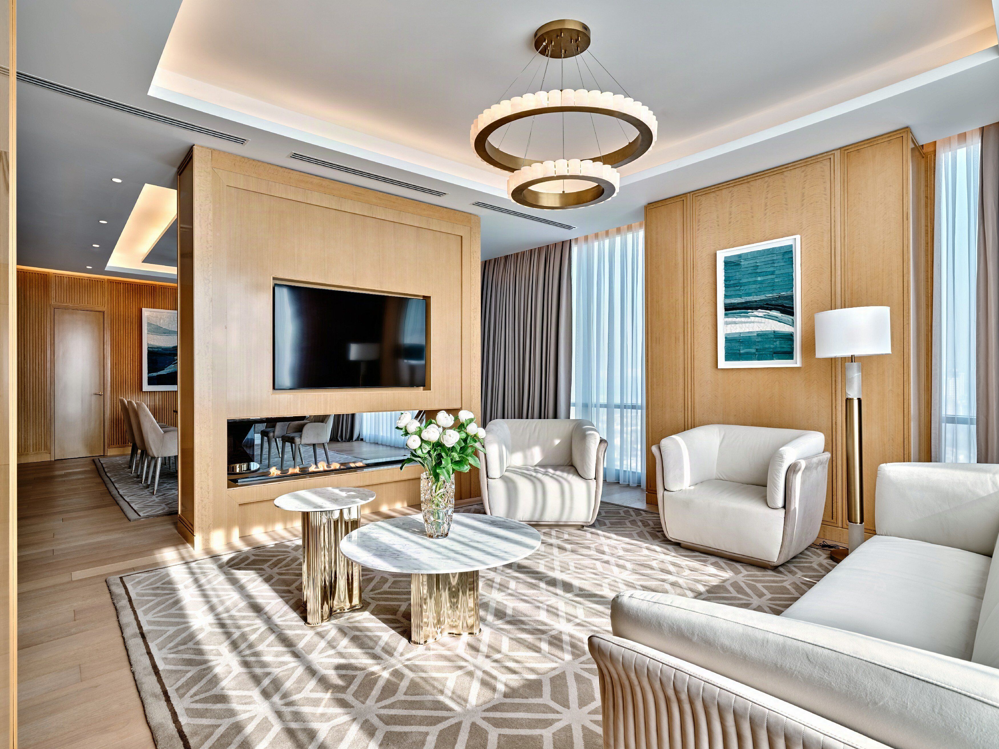 A modern living room with a flat-screen TV, two sofas, a coffee table, and a floor lamp.