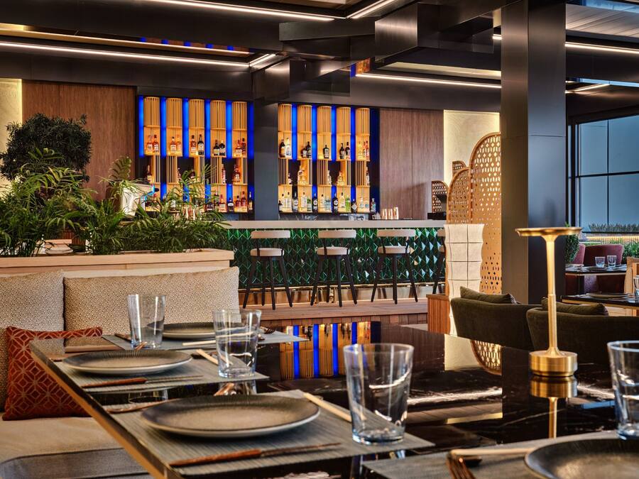 A modern bar area with neatly arranged seating and a variety of liquor bottles.