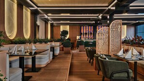 A modern restaurant interior with wooden flooring, cushioned seating, and a bar area. - Crowne Plaza Dushanbe by IHG (Dushanbe)